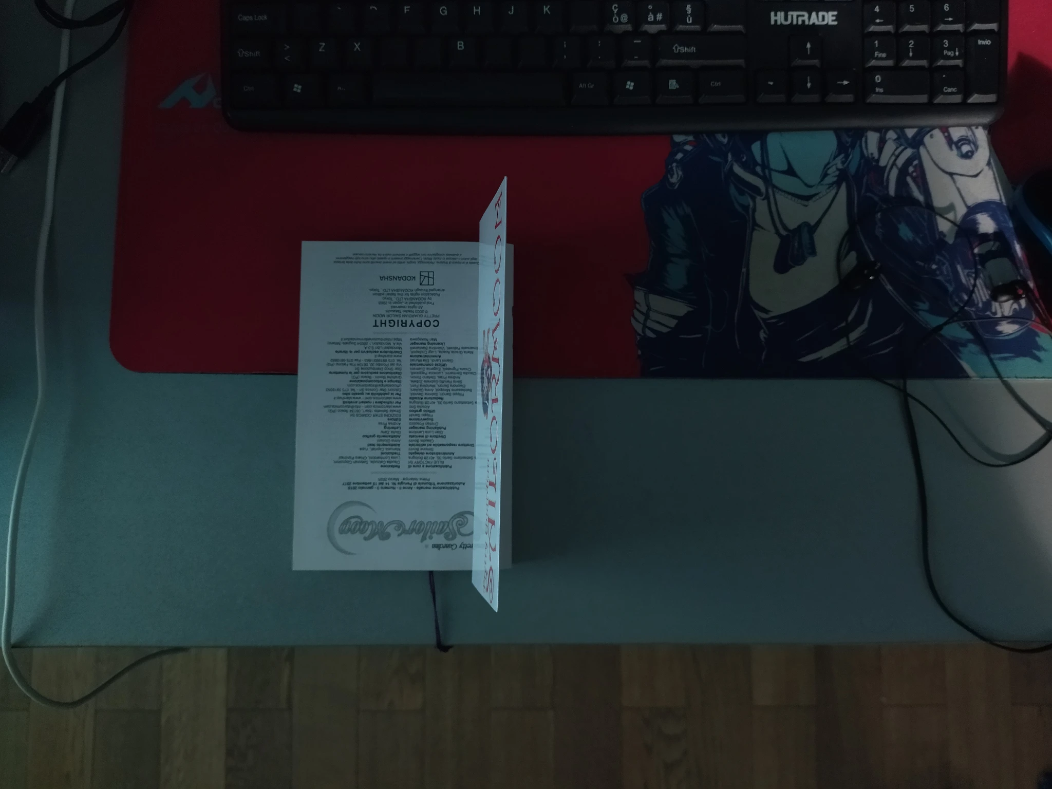 Foto alla mia scrivania, con solo la luce che entra dai balconi e colpisce solo un po' i lati come descritto. Al centro c'è appoggiato il volume 3 di Sailor Moon aperto girato al contrario sulla pagina finale (crediti/copyright). Esposizione della foto volutamente abbassata un pochino per rendere meglio l'idea che sento della poca luce.