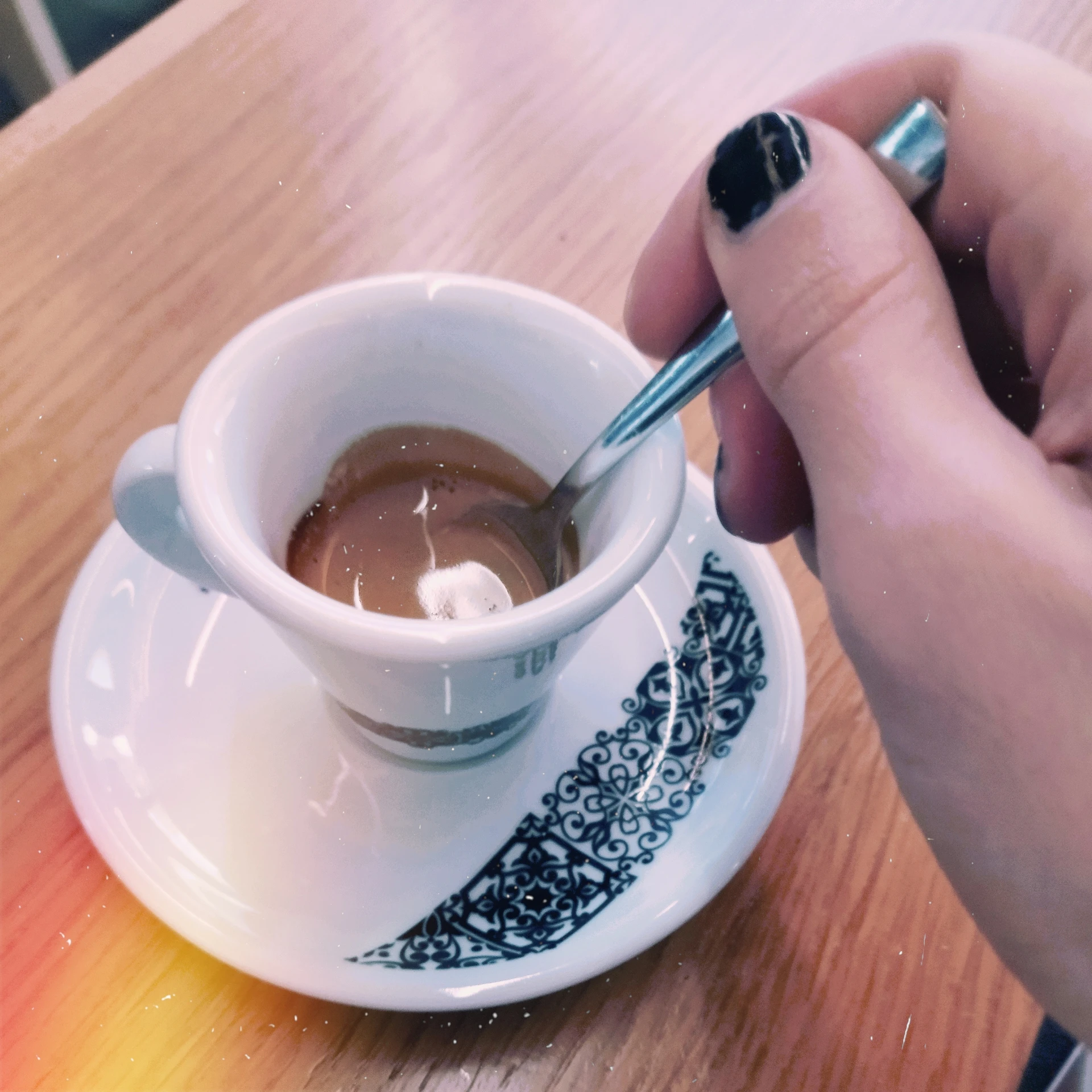 Foto della tazzina di caffè sul tavolo con il cucchiaino in mano mia, filtro film di B612